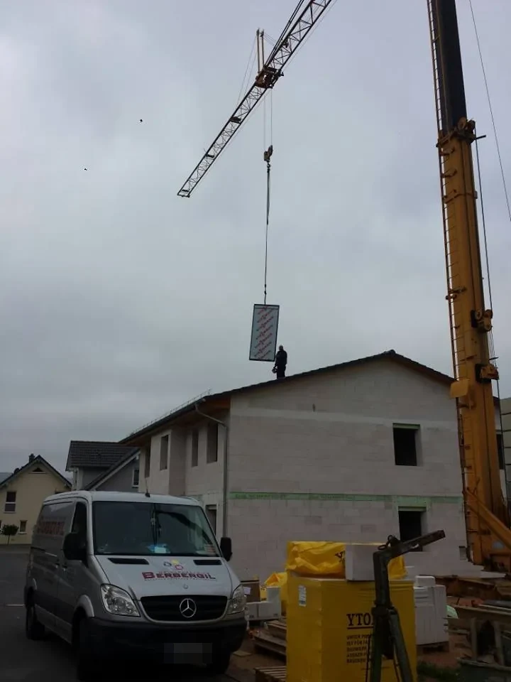 Ein Kran hebt einen Solarkollektor auf das Dach
